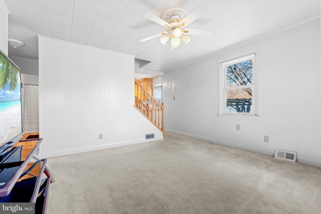 carpeted living room featuring visible vents, stairway, and ceiling fan