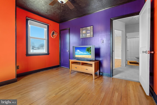 interior space with baseboards, hardwood / wood-style floors, and a ceiling fan