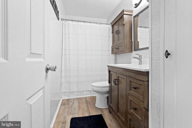 full bath featuring a shower with curtain, toilet, wood finished floors, and vanity