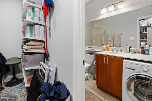 full bathroom featuring toilet, washer / clothes dryer, tiled shower, and vanity