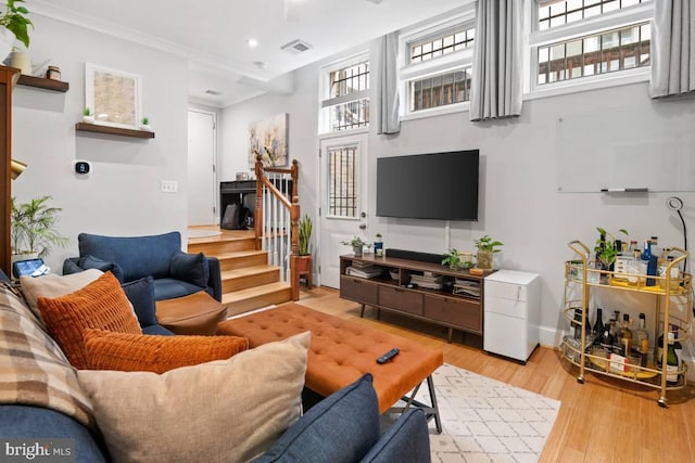 living area featuring visible vents, light wood-style flooring, stairway, crown molding, and recessed lighting