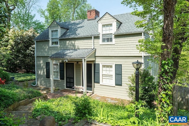 cape cod-style house featuring roof with shingles and a chimney