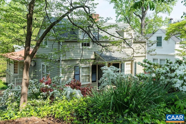 view of front facade featuring a shingled roof and a chimney