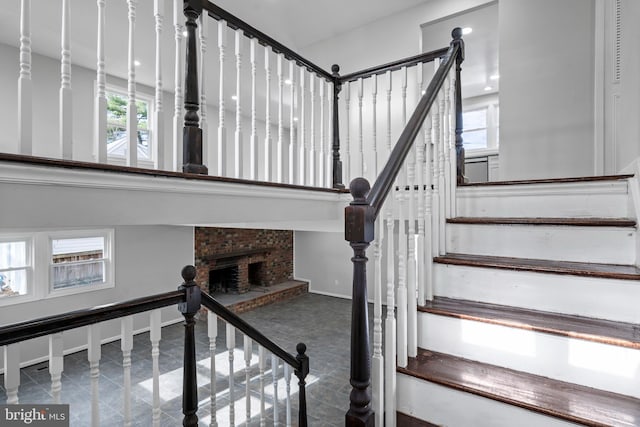 staircase featuring a brick fireplace and baseboards