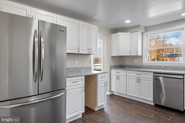 kitchen featuring recessed lighting, stainless steel appliances, white cabinetry, light stone countertops, and wood tiled floor