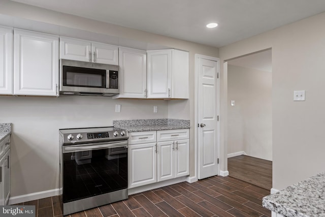 kitchen featuring baseboards, appliances with stainless steel finishes, wood finish floors, and white cabinets