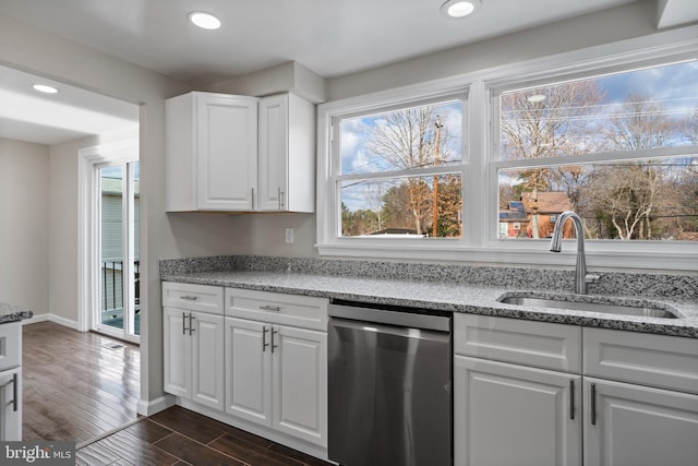 kitchen with stainless steel dishwasher, a sink, white cabinetry, and light stone countertops