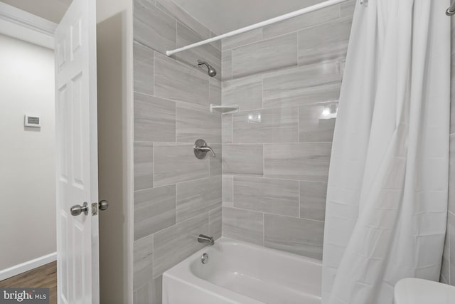 bathroom with toilet, shower / bathtub combination with curtain, baseboards, and wood finished floors