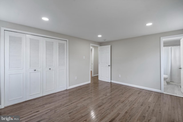 unfurnished bedroom with baseboards, ensuite bathroom, dark wood-type flooring, and recessed lighting