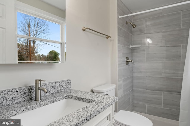 bathroom featuring toilet, a tile shower, and vanity