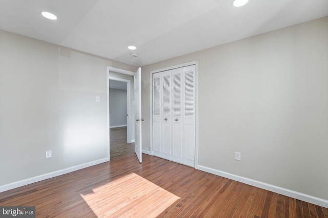 unfurnished bedroom with a closet, recessed lighting, dark wood finished floors, and baseboards