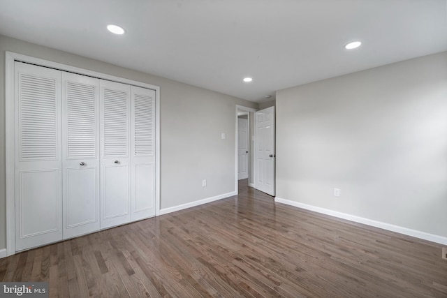 unfurnished bedroom featuring a closet, recessed lighting, wood finished floors, and baseboards