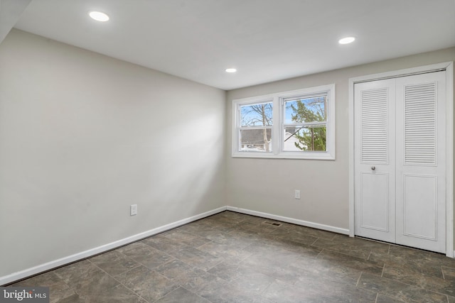 unfurnished bedroom featuring stone finish flooring, baseboards, a closet, and recessed lighting