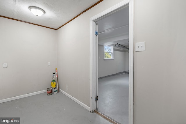 interior space featuring concrete flooring, ornamental molding, a textured ceiling, and baseboards