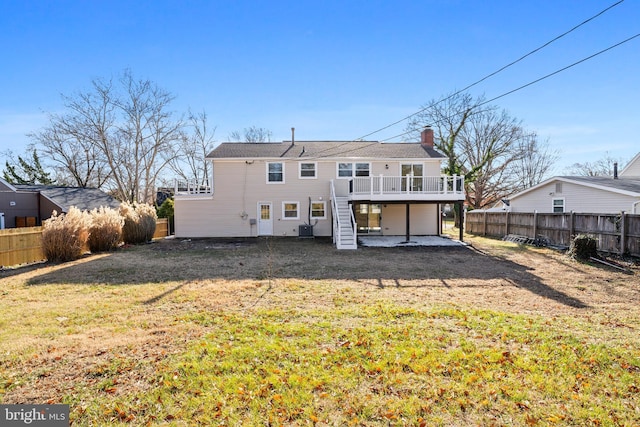 rear view of house with a deck, a fenced backyard, a yard, stairway, and a chimney