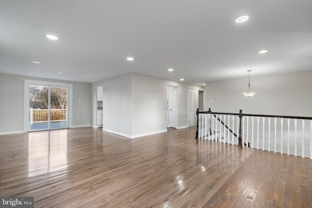 empty room with baseboards, wood finished floors, and recessed lighting