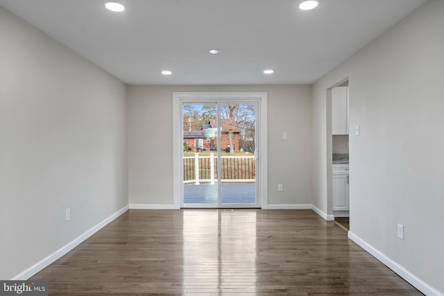 empty room with dark wood-style flooring, recessed lighting, and baseboards