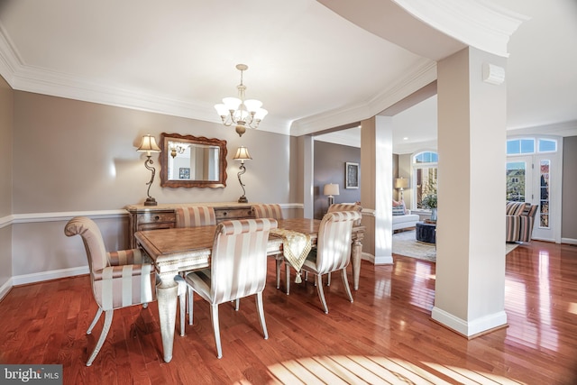 dining space featuring baseboards, ornamental molding, a chandelier, and wood finished floors