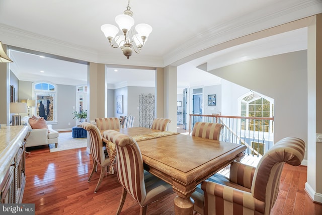 dining area with crown molding, baseboards, wood finished floors, and a notable chandelier