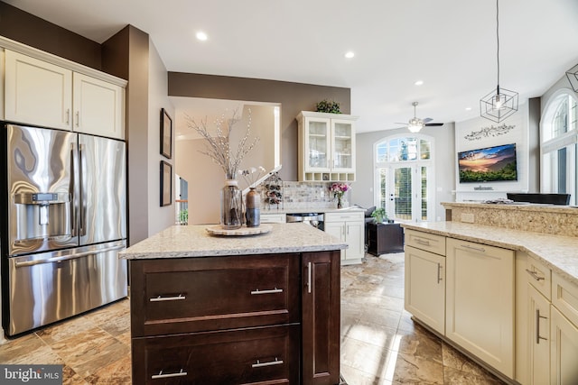 kitchen with light stone counters, decorative light fixtures, stainless steel appliances, decorative backsplash, and glass insert cabinets