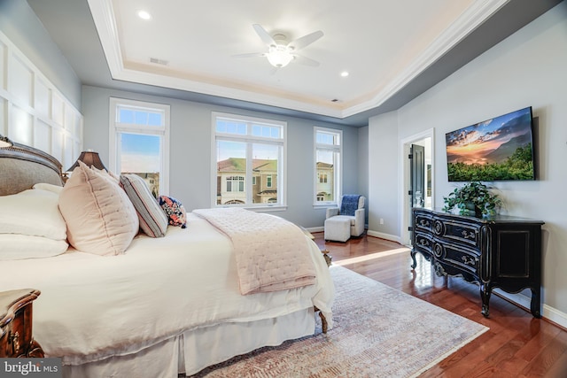 bedroom featuring baseboards, visible vents, dark wood finished floors, a tray ceiling, and crown molding