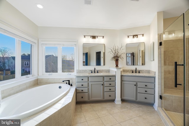 bathroom featuring two vanities, a stall shower, tile patterned flooring, and a sink