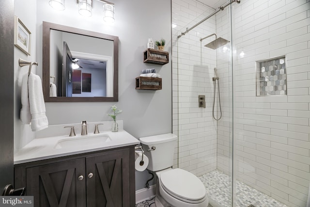 bathroom with a stall shower, baseboards, vanity, and toilet