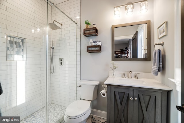 bathroom featuring toilet, baseboards, tiled shower, and vanity