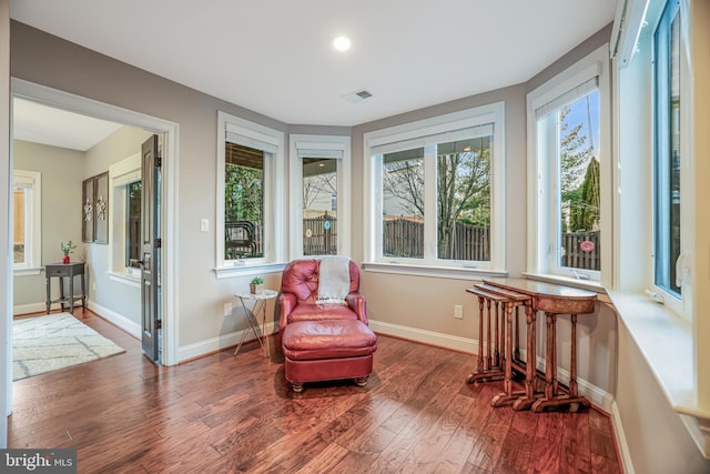 living area with baseboards, visible vents, and dark wood finished floors