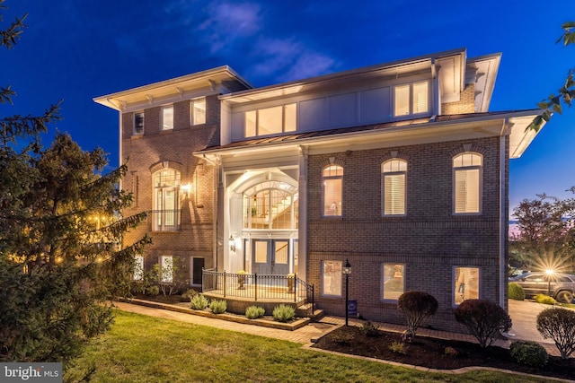 view of front of house featuring a lawn and brick siding