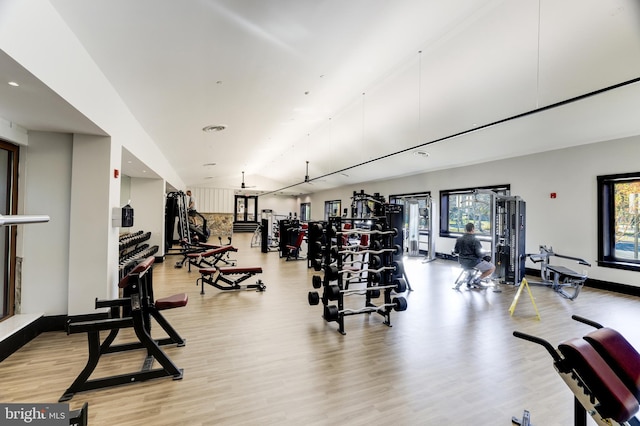 exercise room with a high ceiling and light wood-style floors