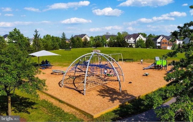 communal playground featuring a residential view and a lawn