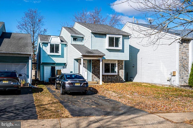 view of front of home featuring stone siding, a shingled roof, and driveway