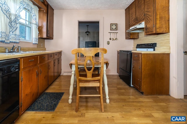 kitchen with light countertops, a sink, under cabinet range hood, and black appliances