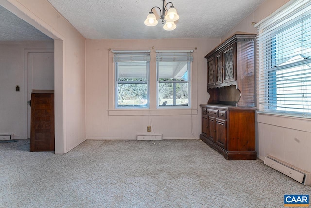 interior space with a notable chandelier, baseboard heating, a textured ceiling, and light colored carpet