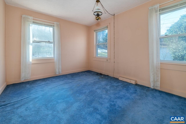 spare room featuring dark colored carpet, a healthy amount of sunlight, and a textured ceiling