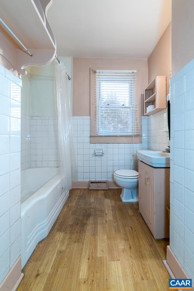 full bath featuring plenty of natural light, tile walls, vanity, and wood finished floors