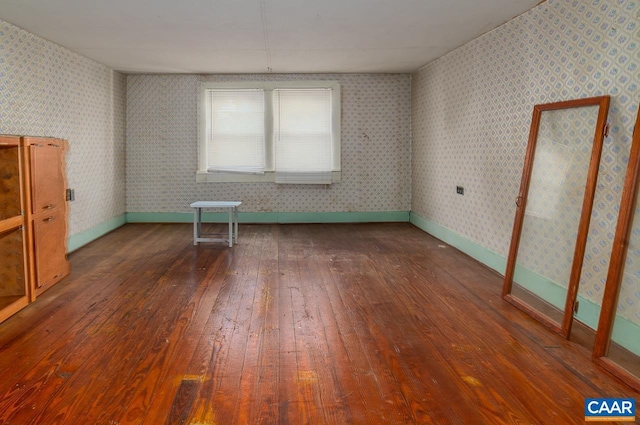 unfurnished room featuring baseboards, dark wood-type flooring, and wallpapered walls