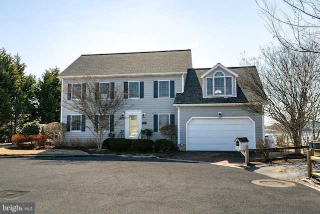 colonial house with a shingled roof, driveway, and an attached garage