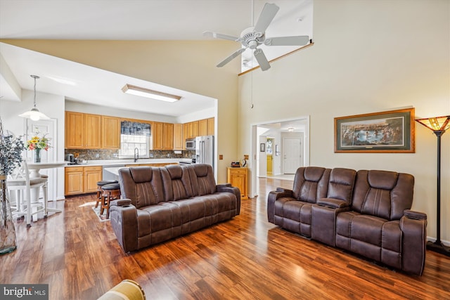 living area featuring ceiling fan, a high ceiling, and dark wood finished floors