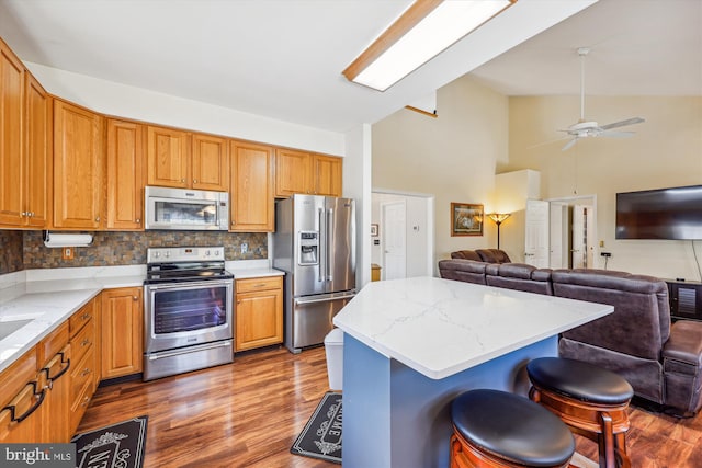 kitchen featuring a kitchen bar, light stone counters, stainless steel appliances, and open floor plan