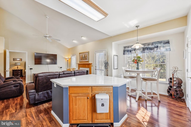 kitchen featuring dark wood finished floors, decorative light fixtures, vaulted ceiling, light countertops, and a fireplace