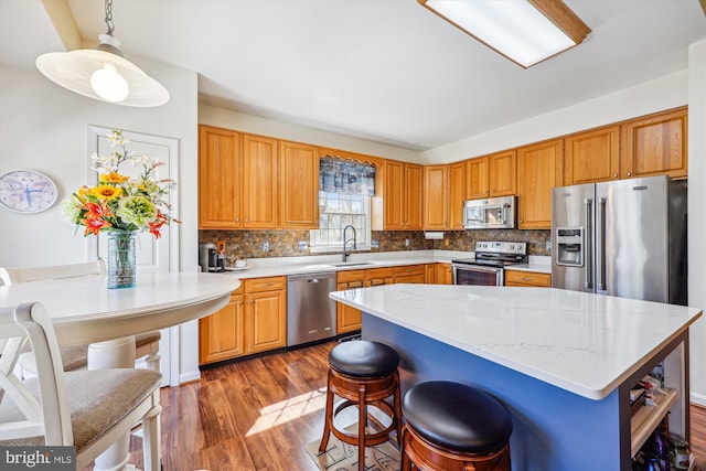 kitchen with stainless steel appliances, dark wood-style flooring, a sink, and decorative backsplash