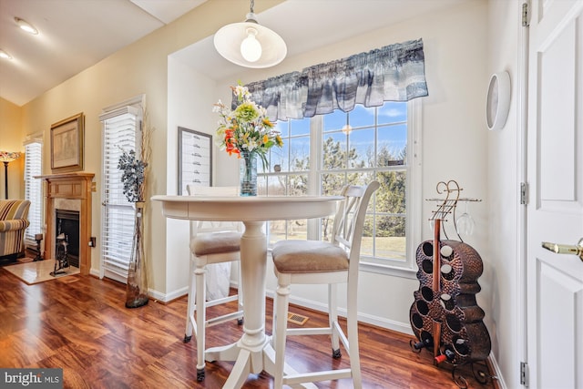 dining room with a fireplace with flush hearth, baseboards, and wood finished floors