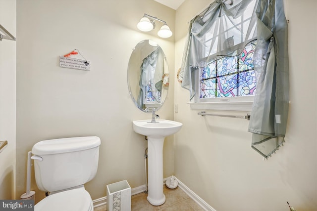 half bathroom with toilet, tile patterned flooring, and baseboards