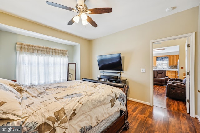 bedroom with dark wood-type flooring, a ceiling fan, and baseboards