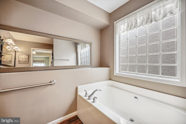 bathroom with a garden tub and baseboards