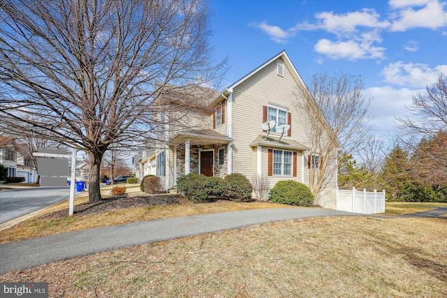 traditional-style house featuring a front lawn and fence