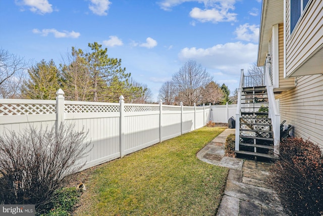 view of yard with a fenced backyard and stairway