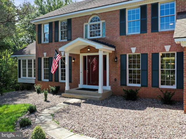 georgian-style home with brick siding and a shingled roof